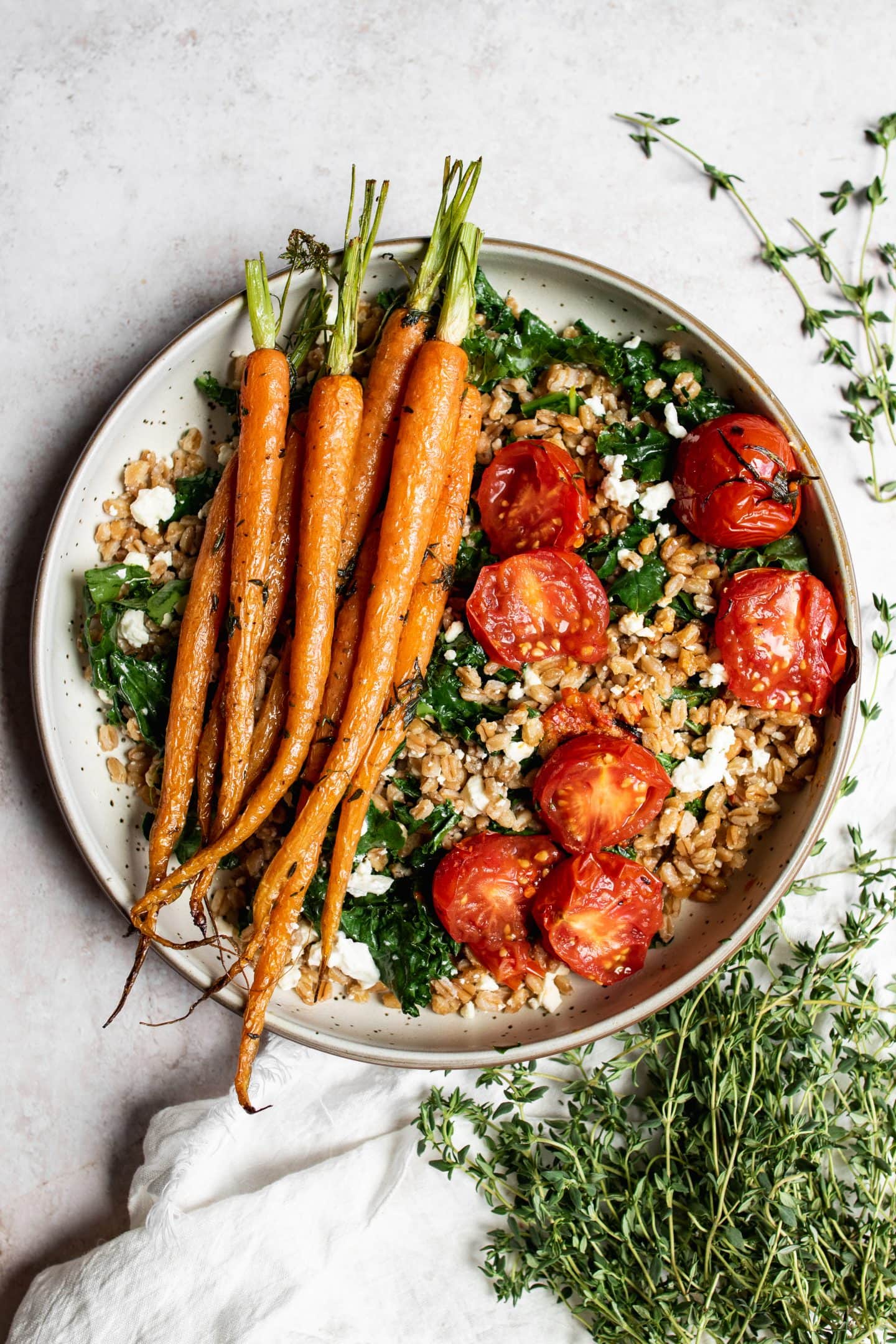 Composed farro bowl with kale, tomatoes, and roasted carrots