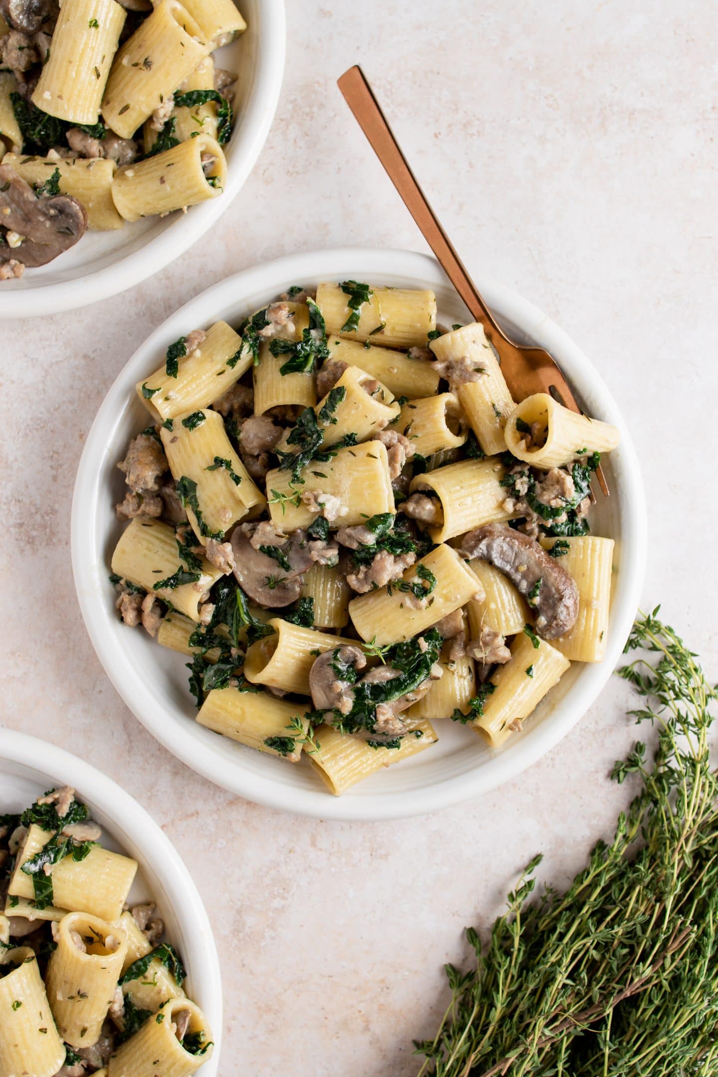 bowls of mushroom, sausage, and kale pasta
