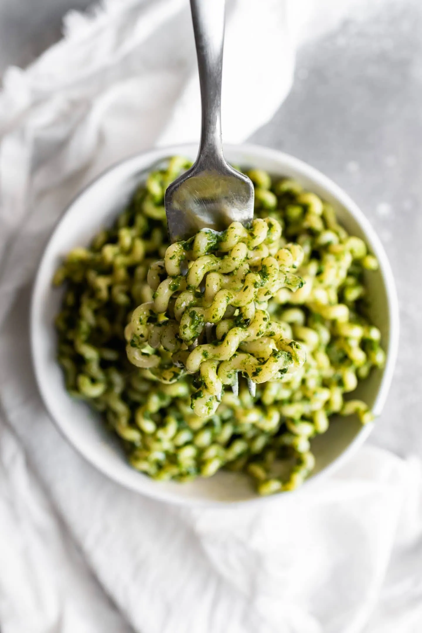 bowl of long fusilli covered in spinach pesto
