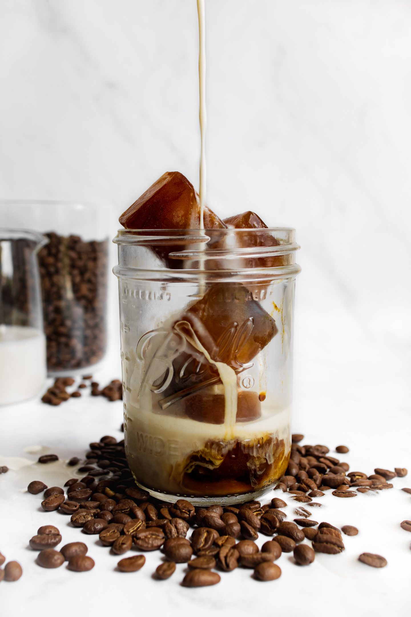 coffee cubes in a glass with hot oat milk being poured over
