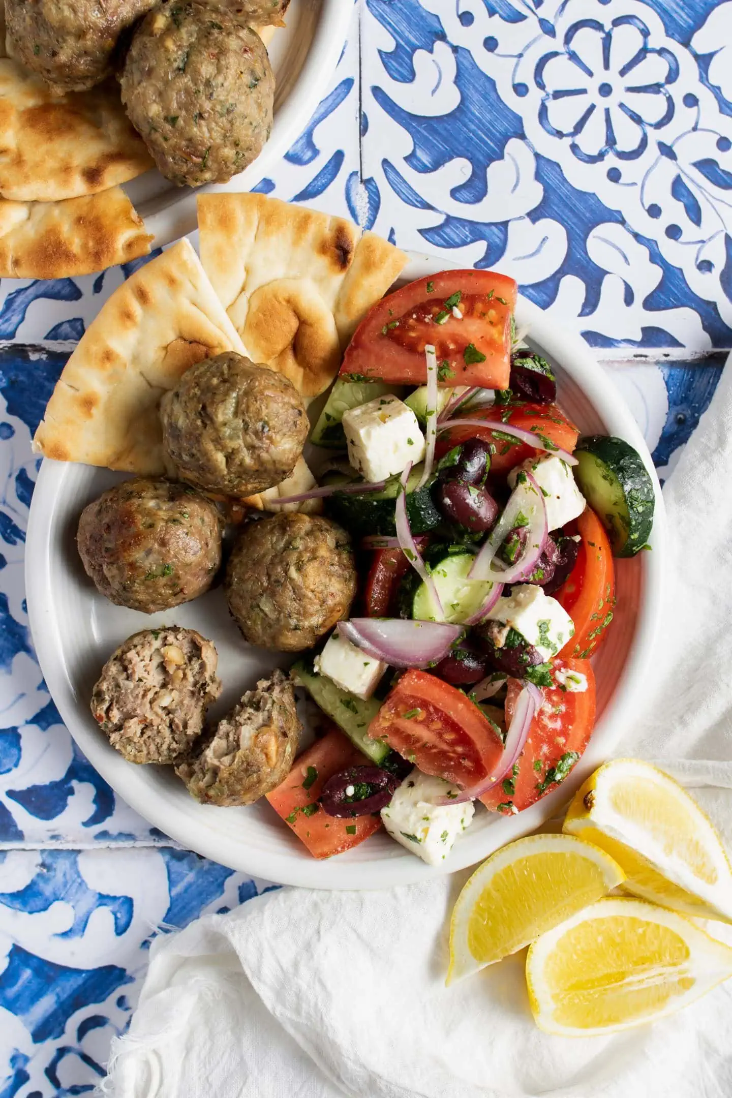 plate of greek lamb meatballs on the side of a greek salad