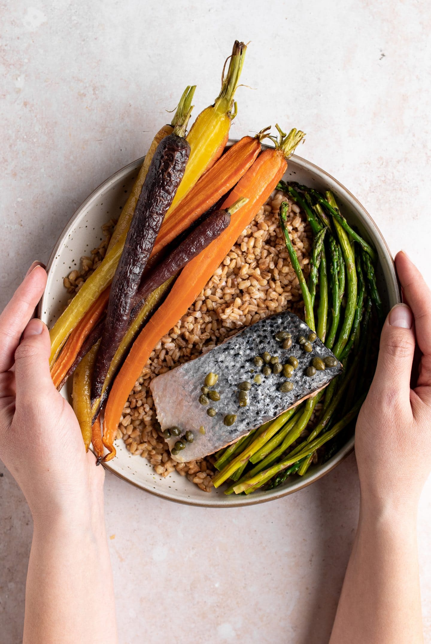 composed grain bowl of lemon caper salmon with roasted vegetables