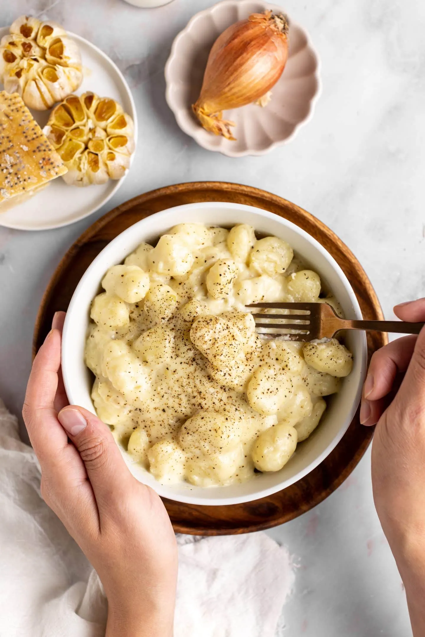 eating from a bowl of creamy roasted garlic gnocchi