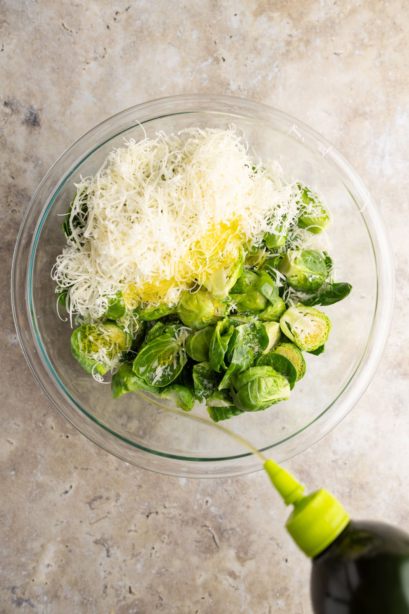 step by step: seasoning the raw cut Brussels sprouts with parm, salt, pepper, and a heavy dose of olive oil.