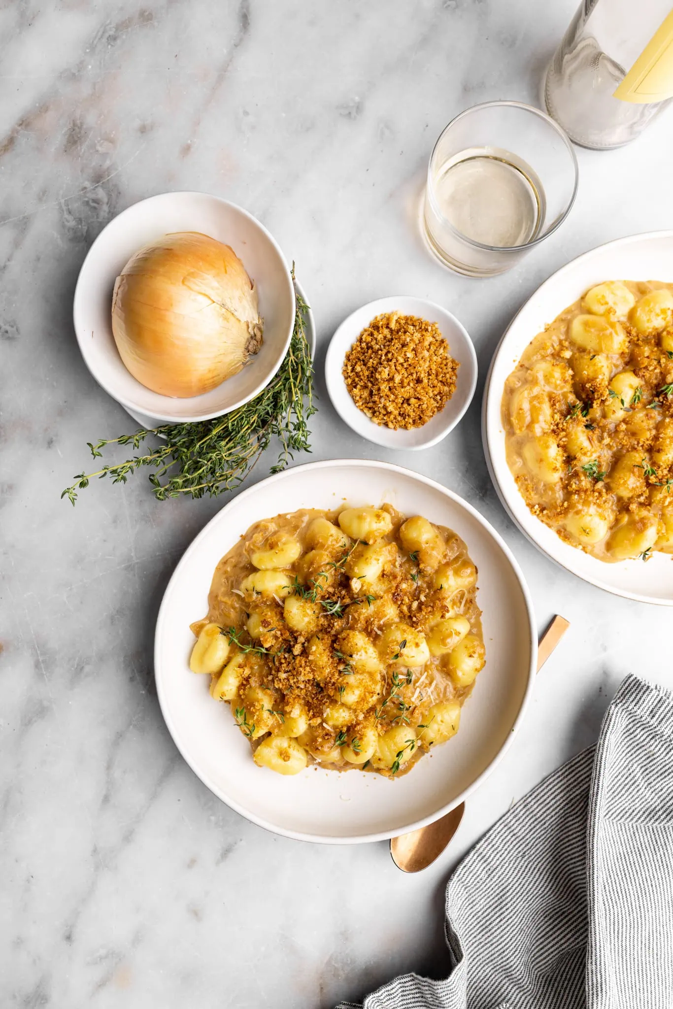 2 bowls of French onion gnocchi with crispy bread crumbs topped with thyme