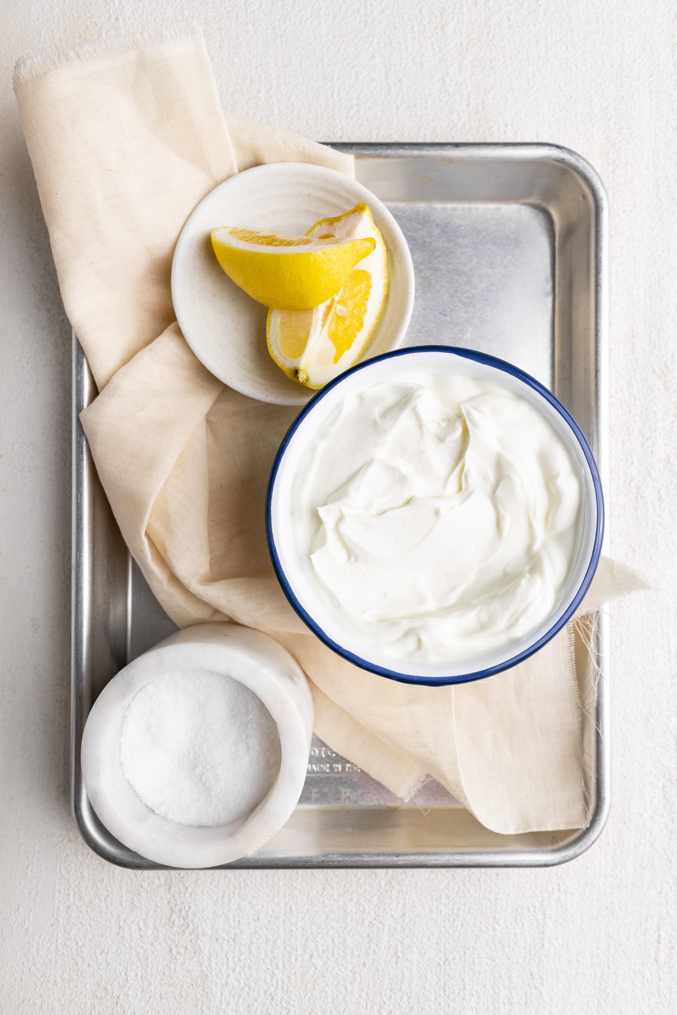 ingredients for labneh;  greek yogurt, salt, lemon, and a cheese cloth