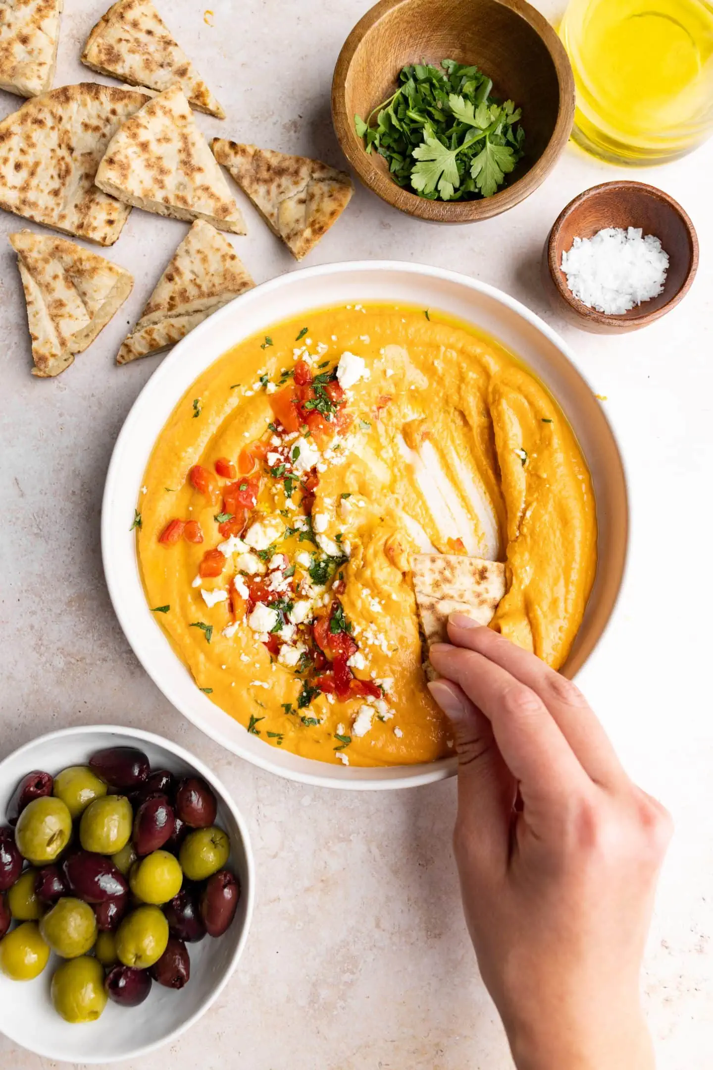 dipping pita bread in roasted red pepper hummus