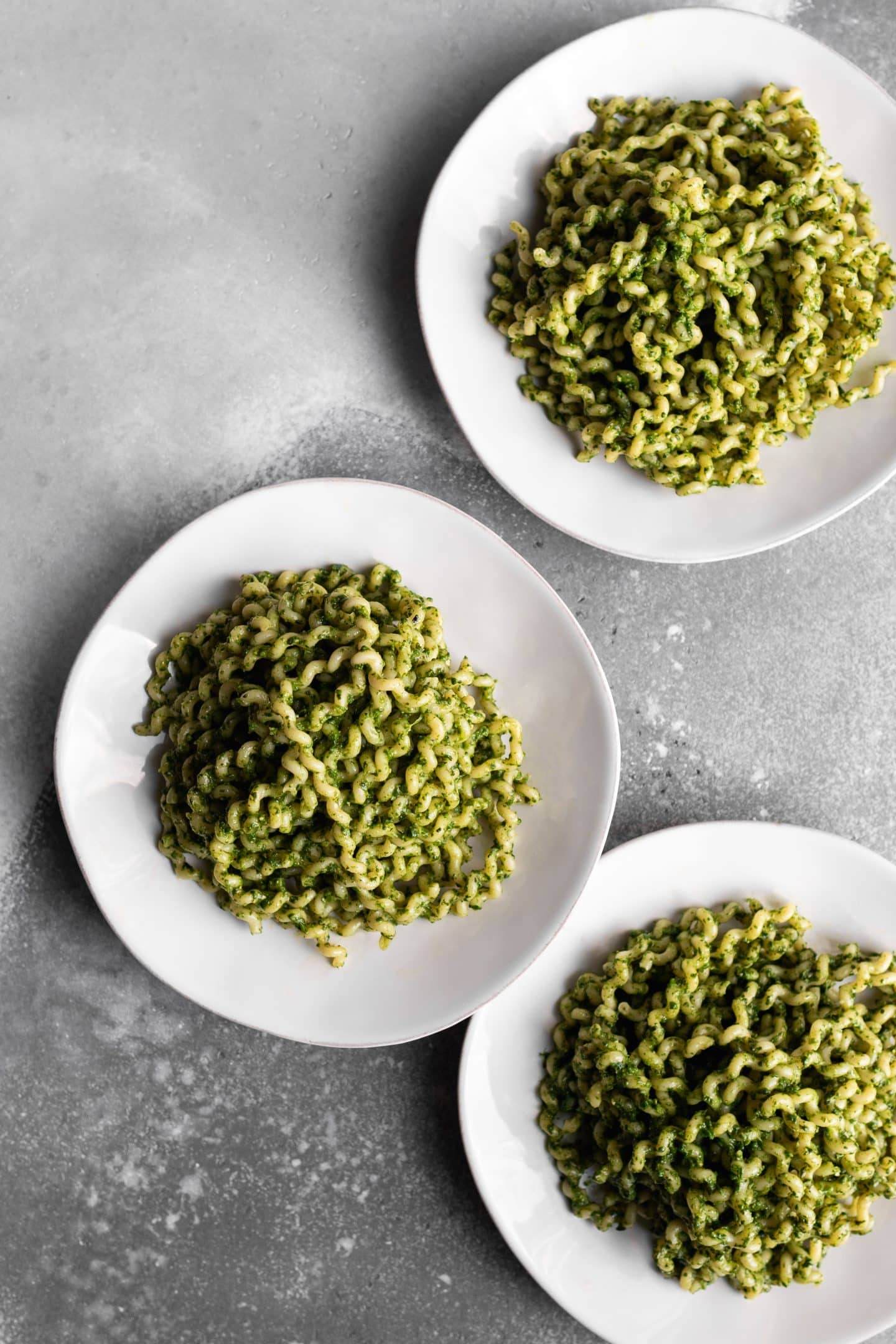 3 plates of spinach pesto over long fusilli