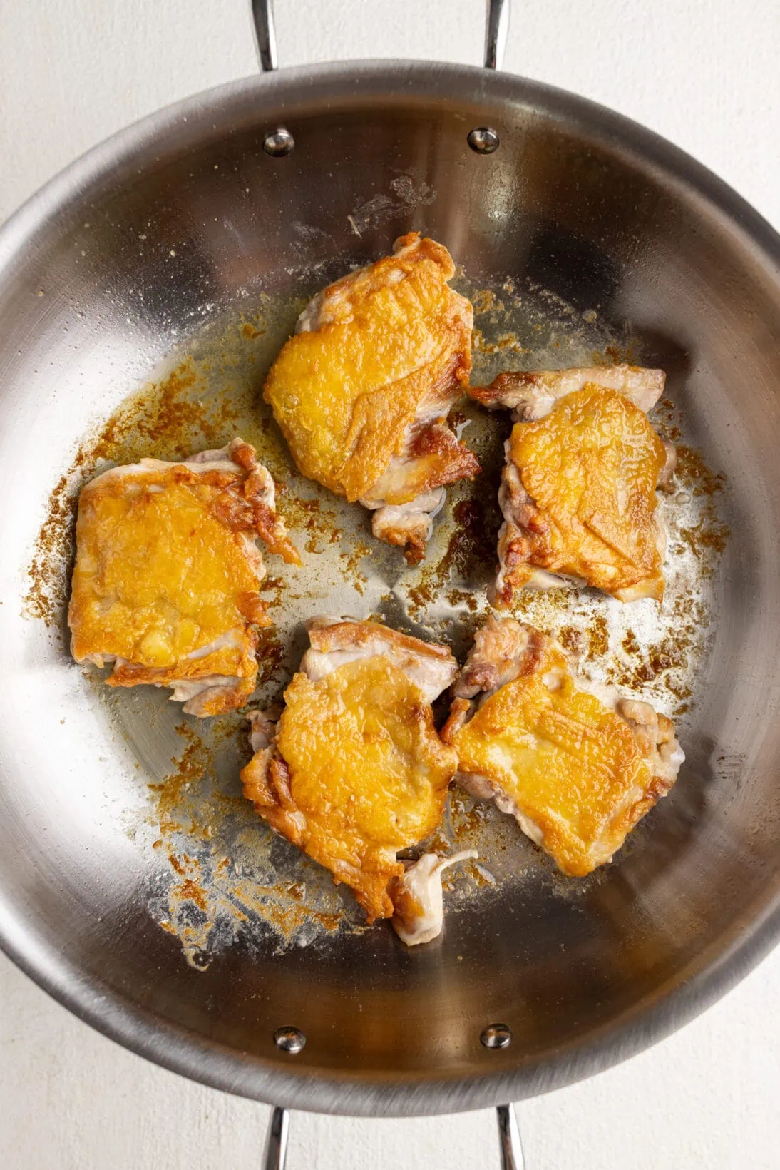 flipped chicken in a stainless steel pan with crispy skin.