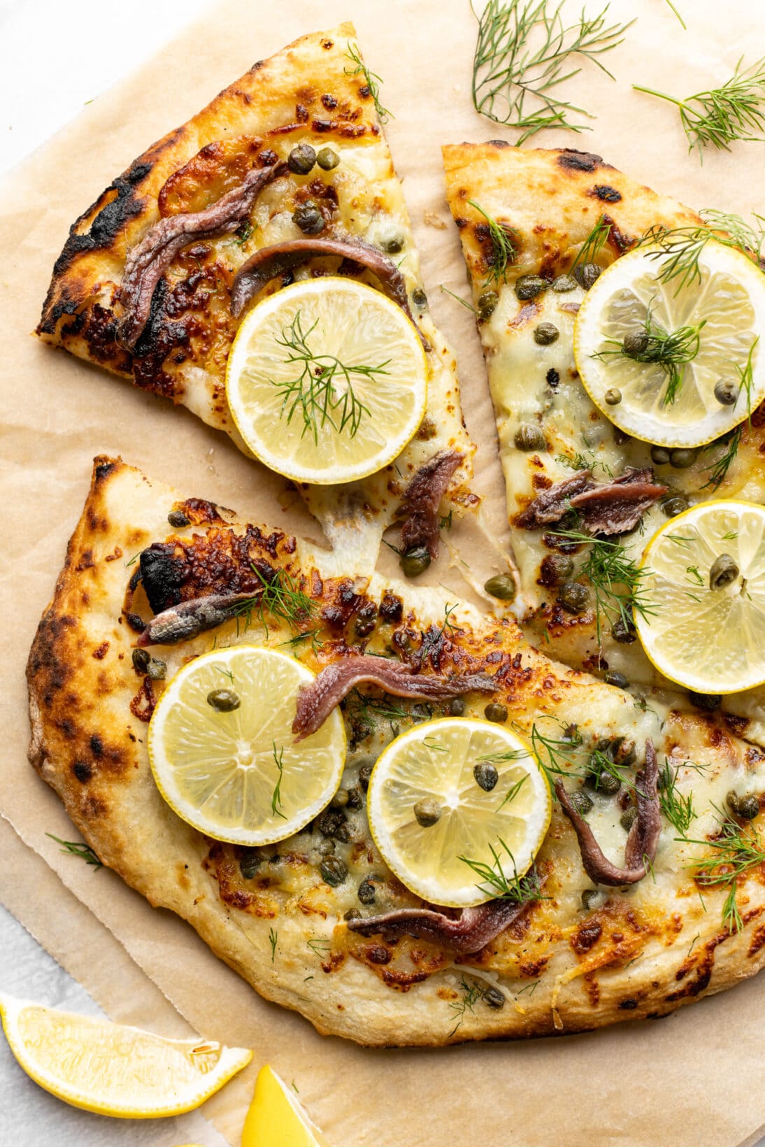 lemon anchovy pizza, a slice being removed with a cheese pull. 