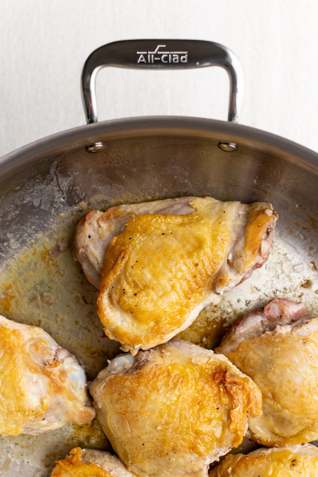 crispy chicken thighs seared in a stainless steel pan