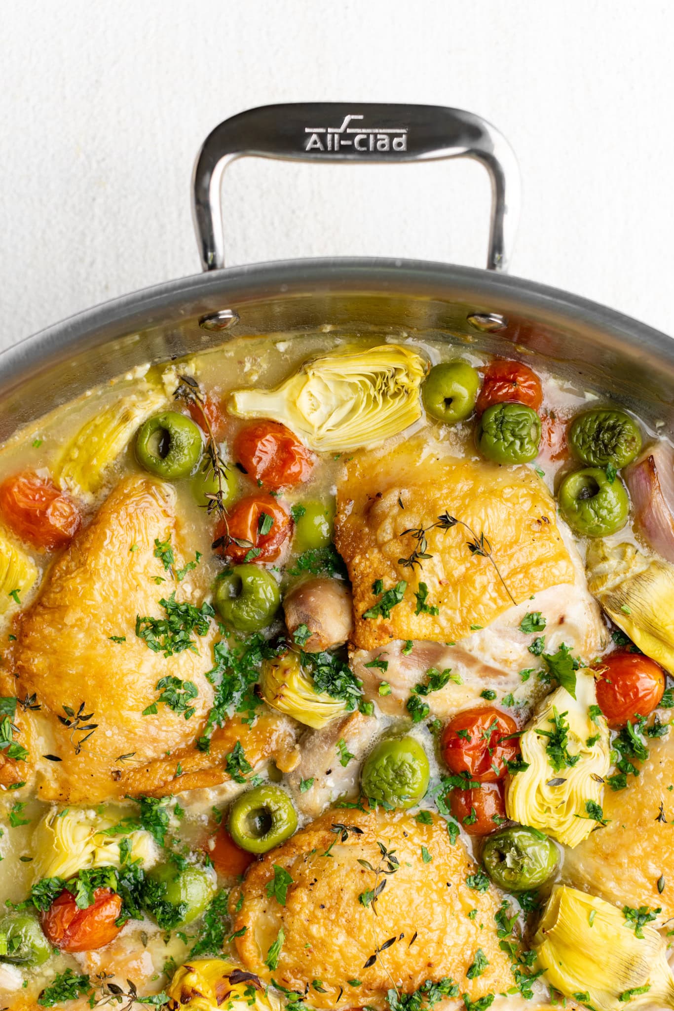 up close chicken provençal with artichokes, olives, tomatoes, shallots in an All-Clad Sunday Supper pan
