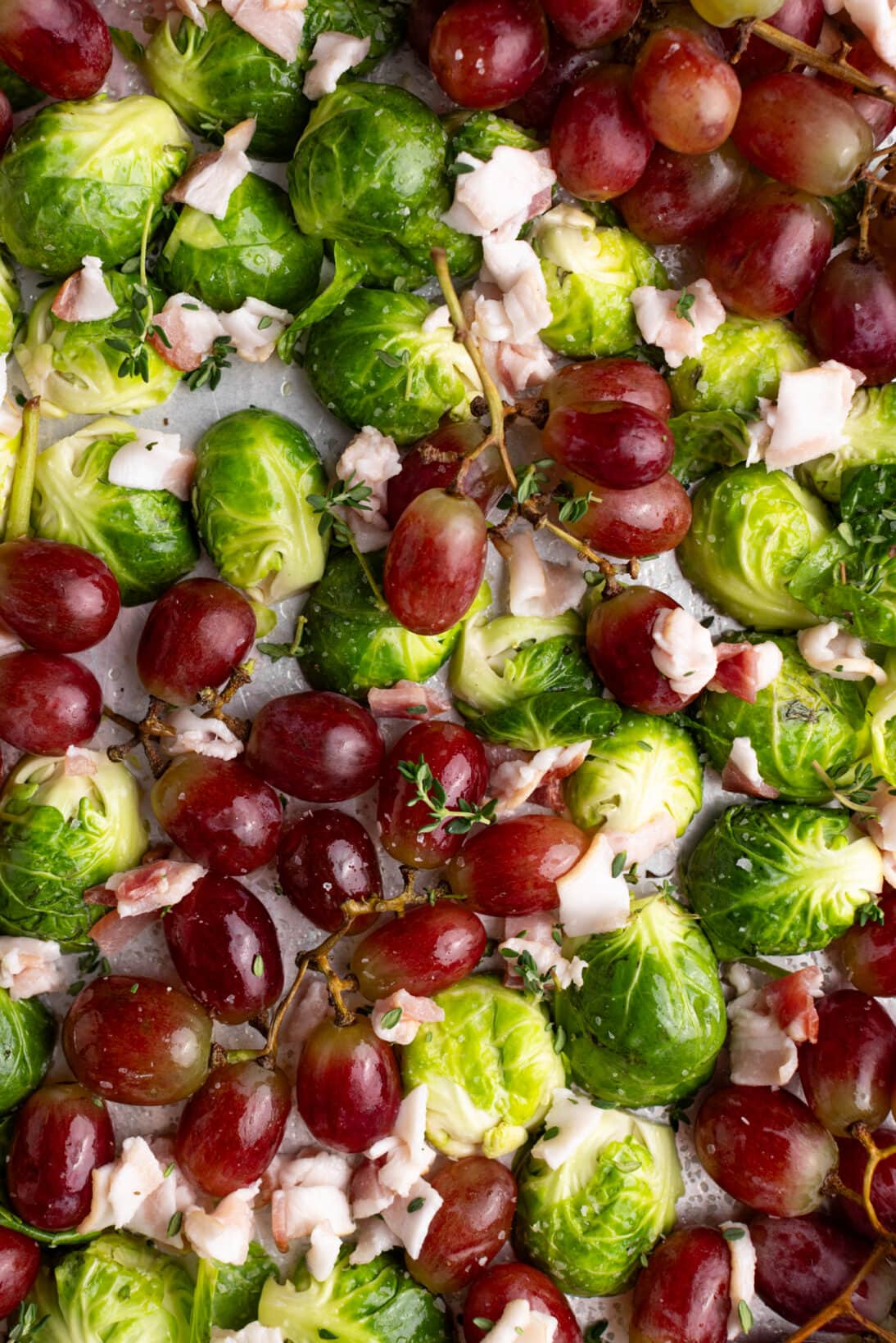 grapes, brussels sprouts, and raw bacon ona. sheet tray, raw.