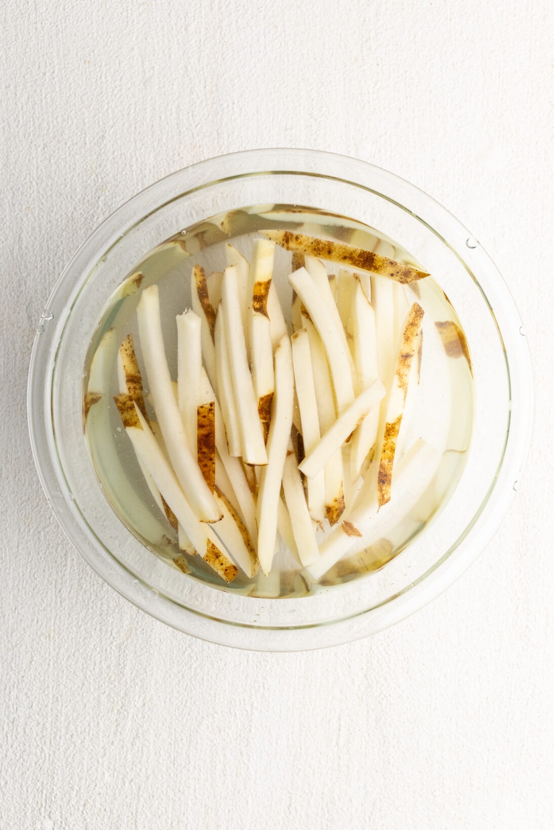 raw potatoes cut into fries soaking