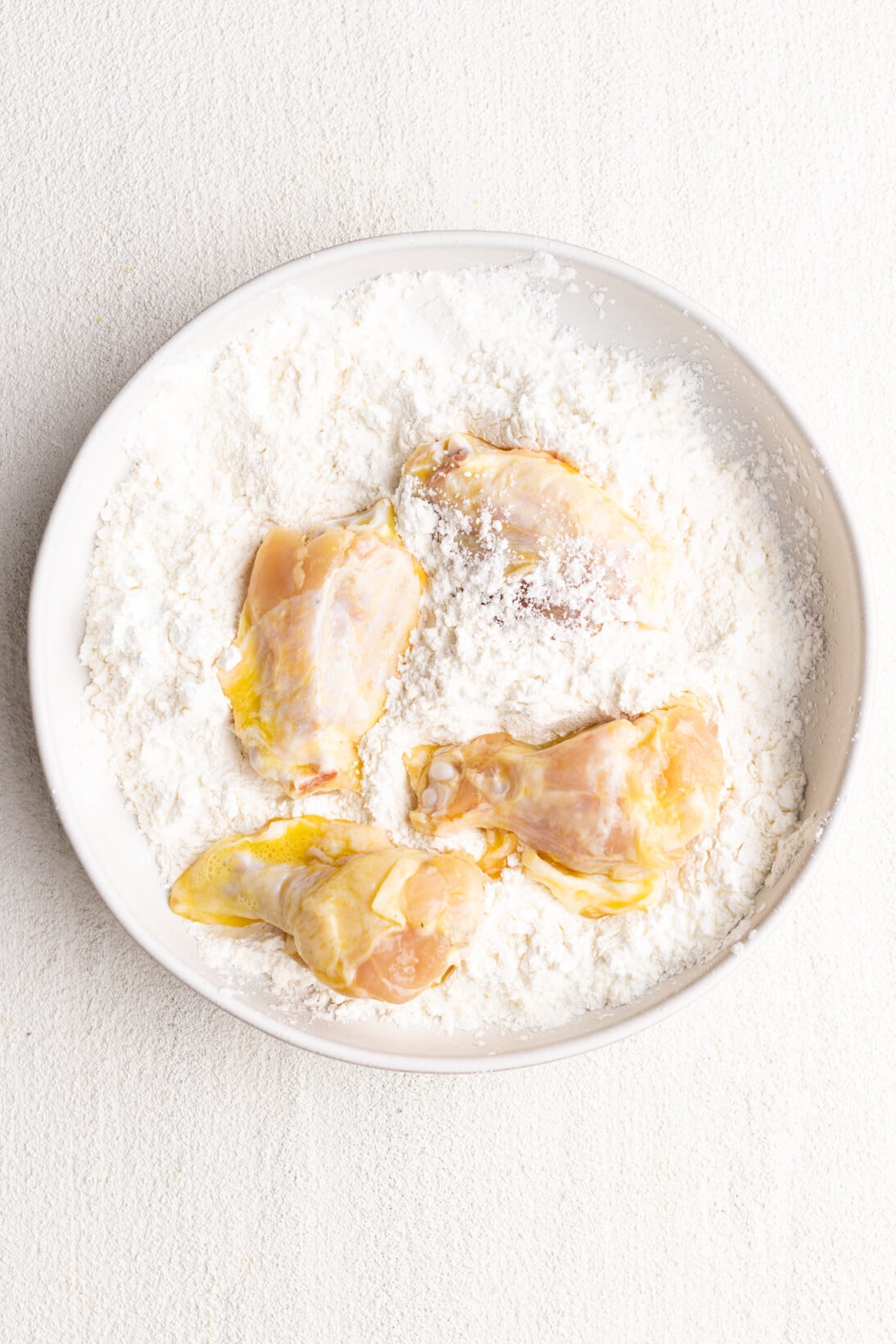 egg coated wings getting coated in a flour cornstarch coating