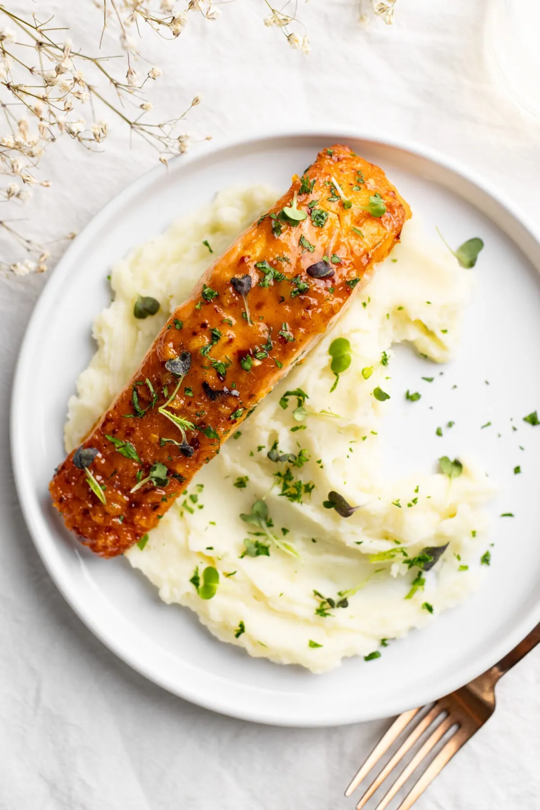 honey mustard salmon over a bed of creamy mashed potatoes topped with parsley and micro greens. 