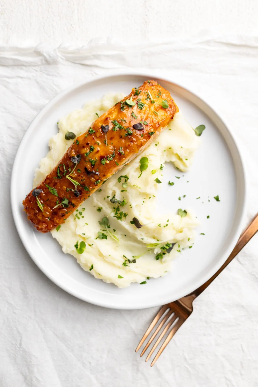 honey mustard salmon over a bed of creamy mashed potatoes topped with parsley and micro greens. 