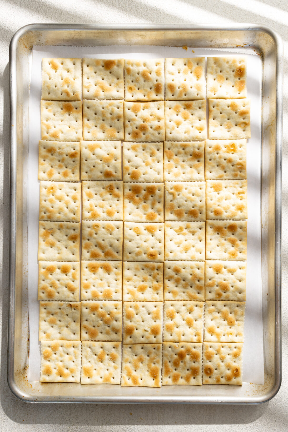 saltines laid out on a parchment lined sheet pan