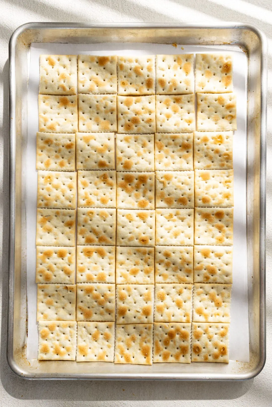 saltines laid out on a parchment lined sheet pan