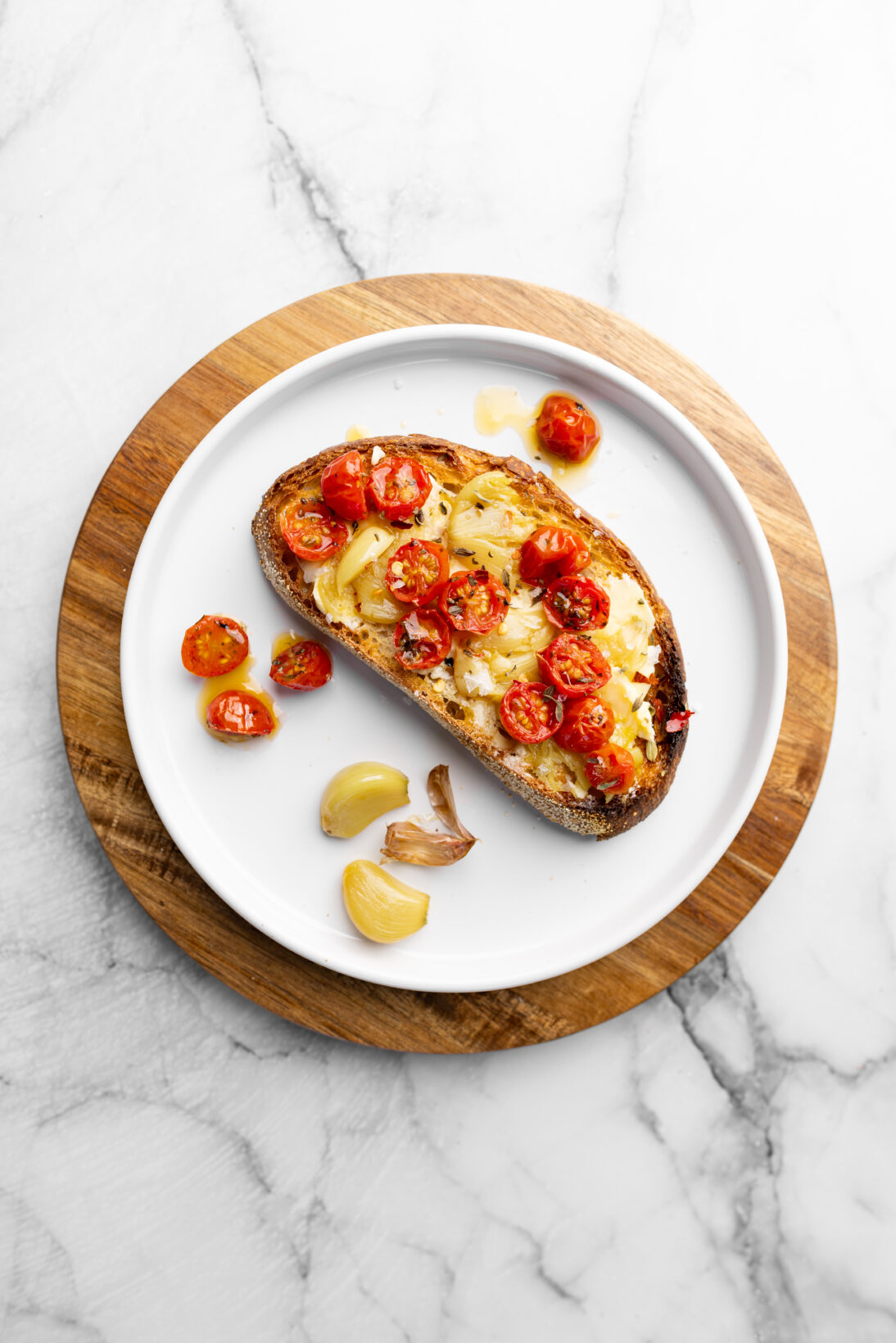 a crusty piece of sourdough coated in salted butter, crushed garlic confit, and tomato confit.