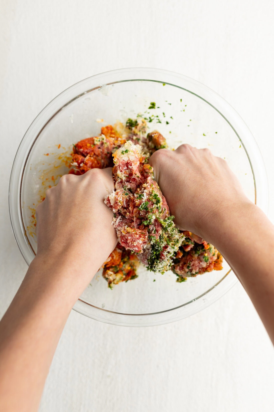 mixing the meatball ingredients in a bowl by hand