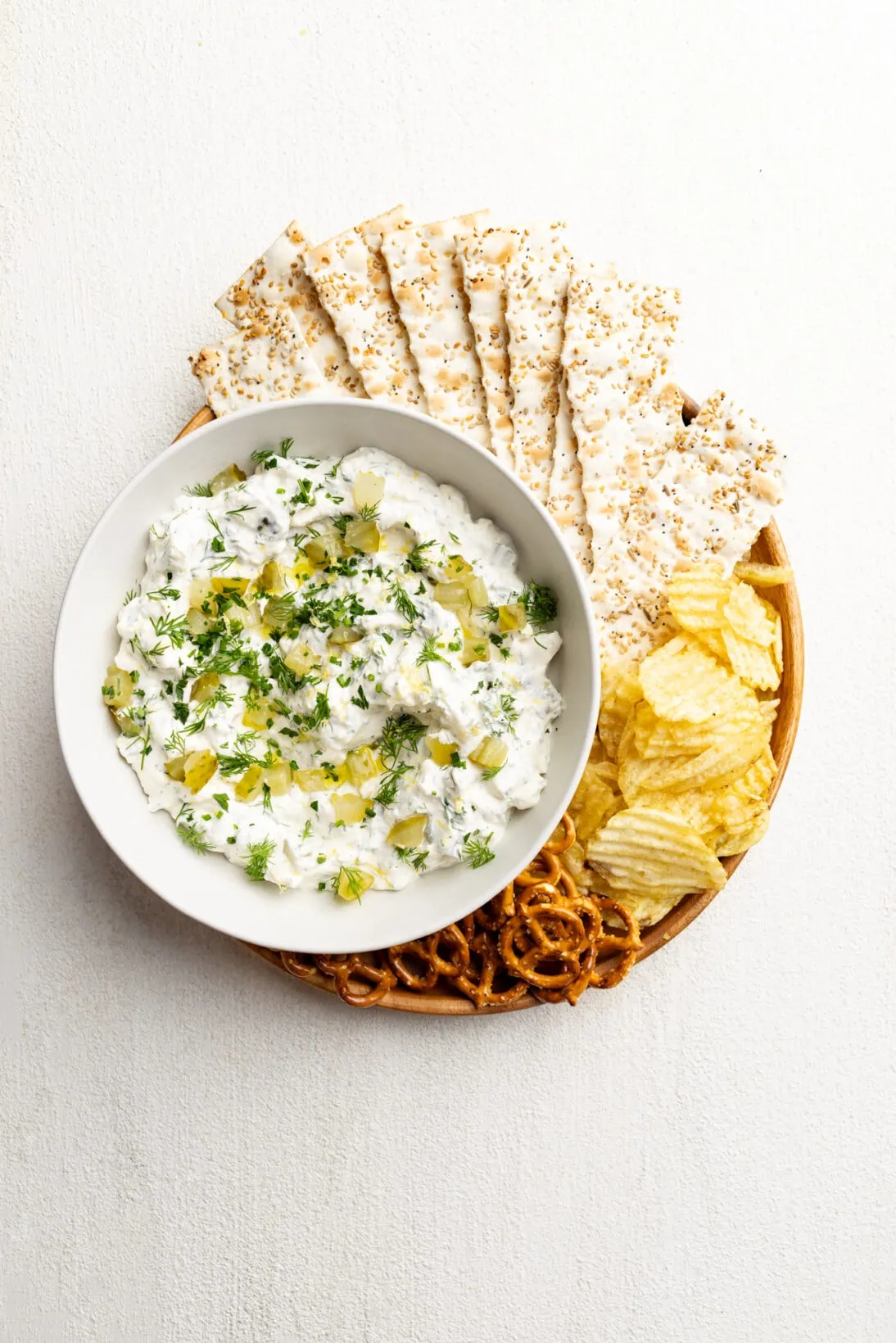 plate of dill pickle dip, everything flatbread crackers, chips and pretzels. 