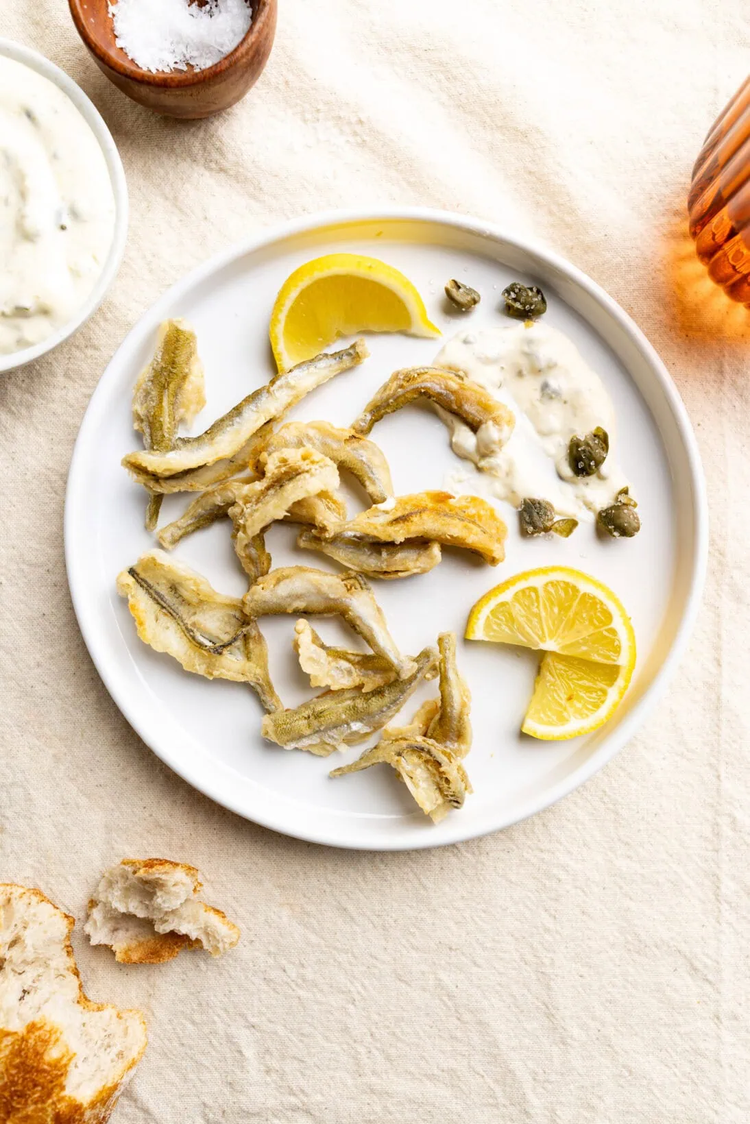 plate of fried smelt with some lemon caper aioli and fresh lemon wedges.