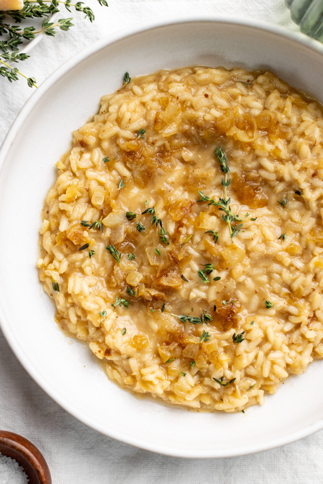 up close bowl of french onion risotto topped with caramelized onions and thyme.