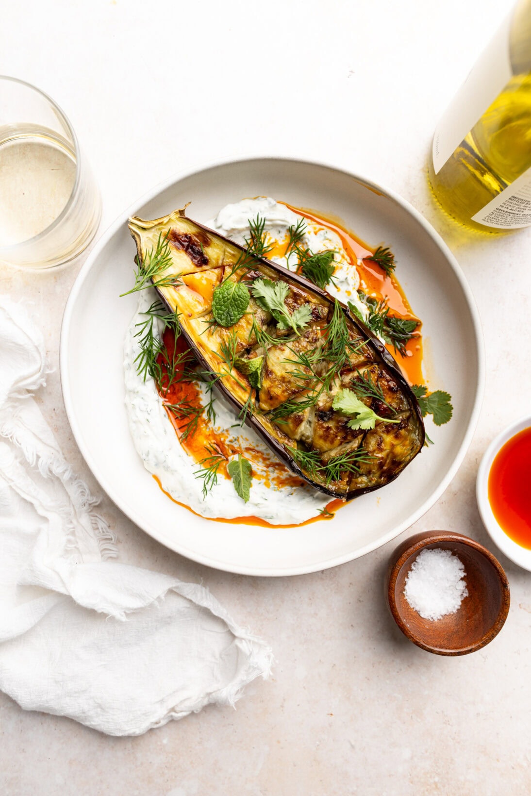 roasted eggplant laying on a bed of garlicky herb yogurt drizzled with a harissa oil