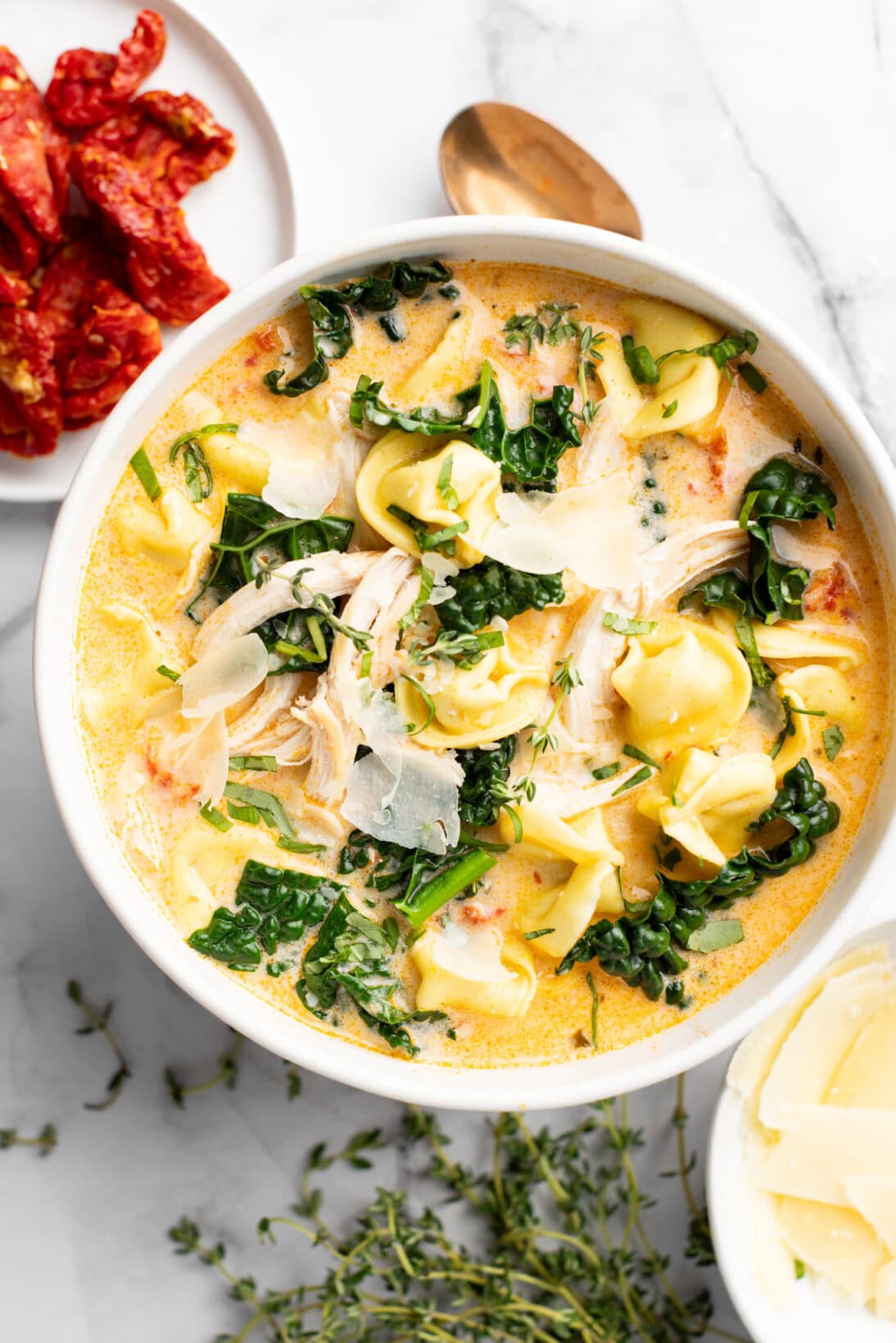 marry me chicken soup with tortellini, kale, and shredded chicken, topped with freshly shaved parm and basil.