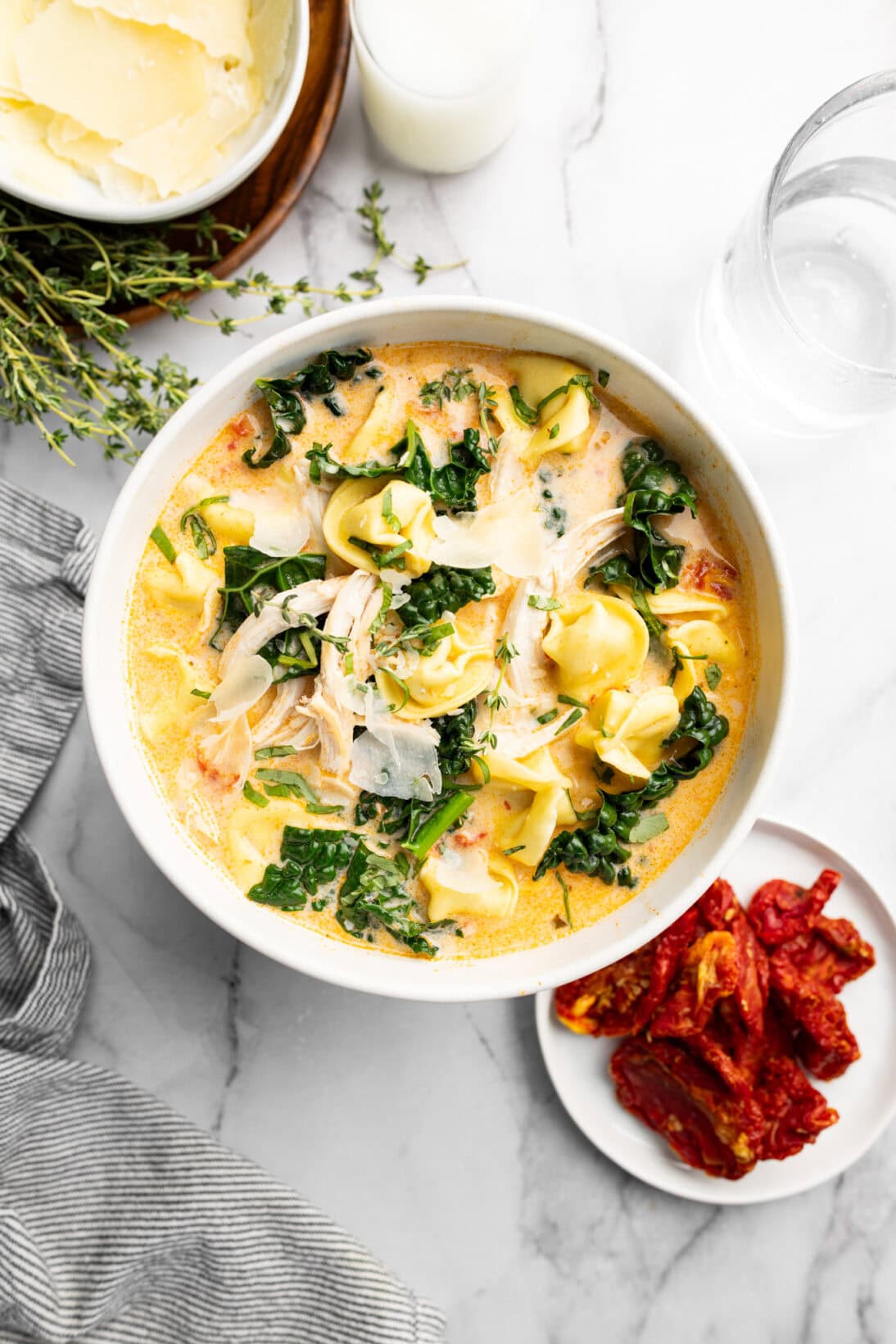 marry me chicken soup with tortellini, kale, and shredded chicken, topped with freshly shaved parm and basil.