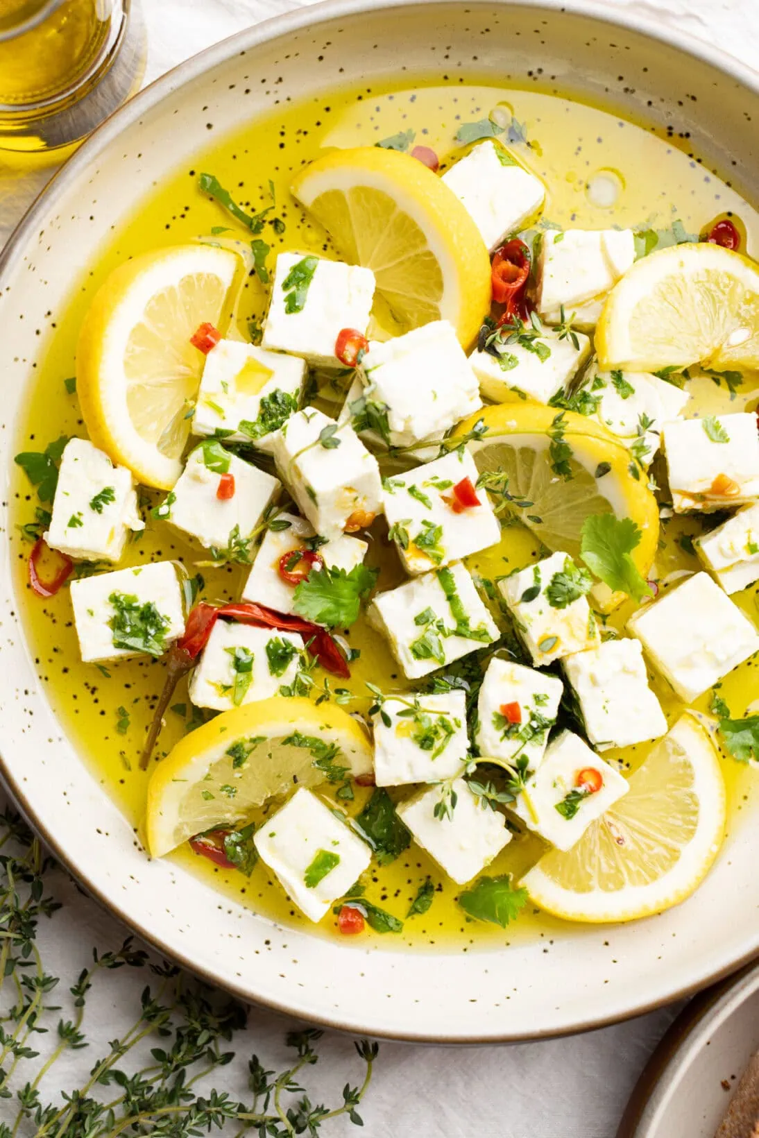 up close creamy marinated feta in a bowl garnished with lemons