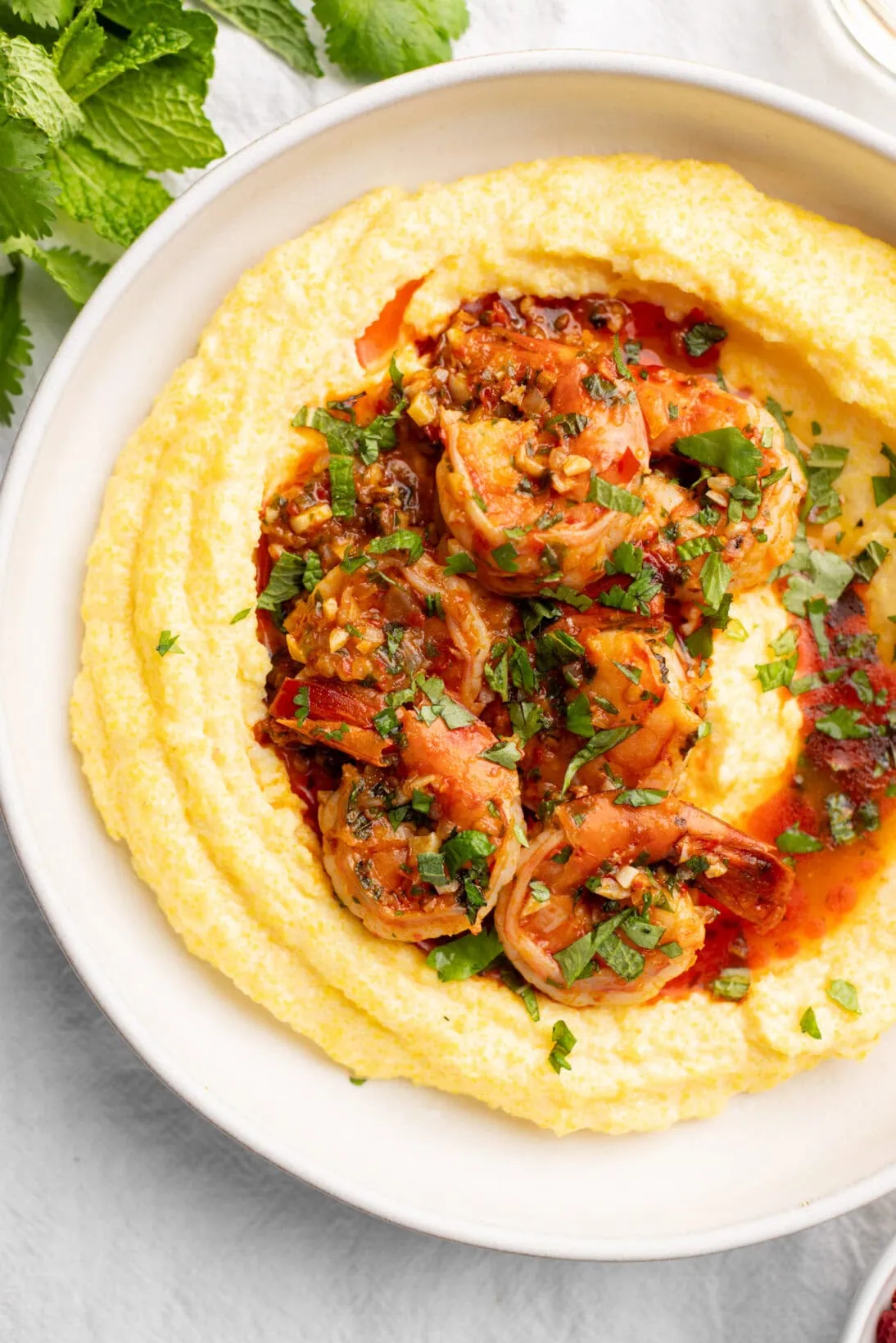 bowl of harissa shrimp over creamy polenta topped with herbs
