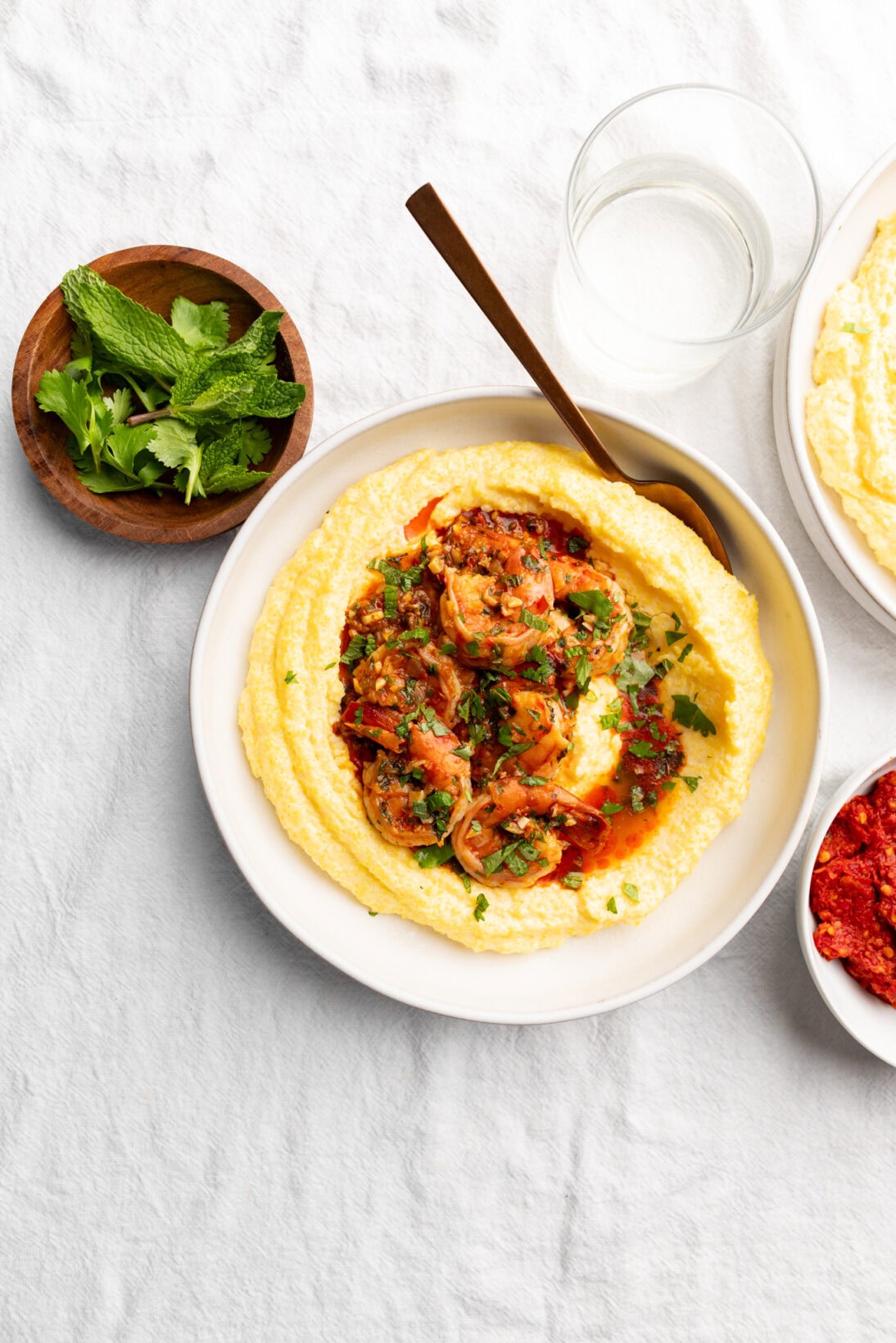 bowl of harissa shrimp over creamy polenta topped with herbs