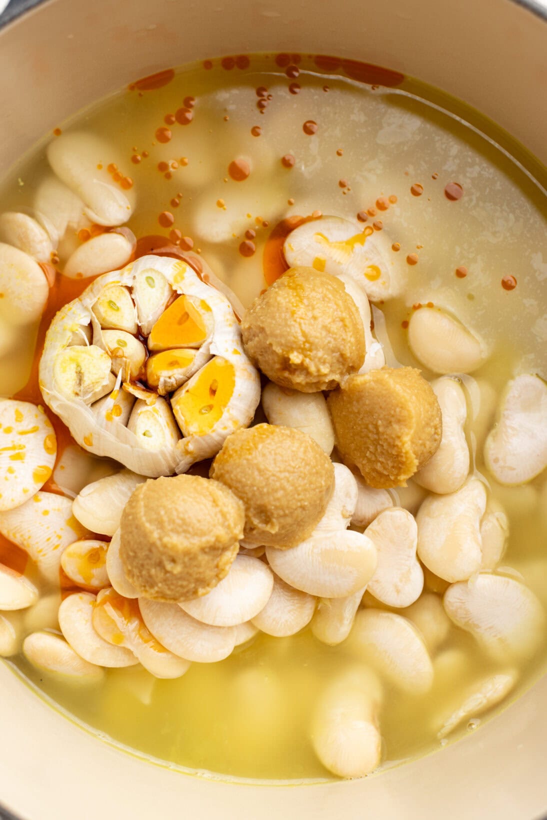 dutch oven filled with the hydrated lima beans, garlic bulb, miso, and Calabrian oil