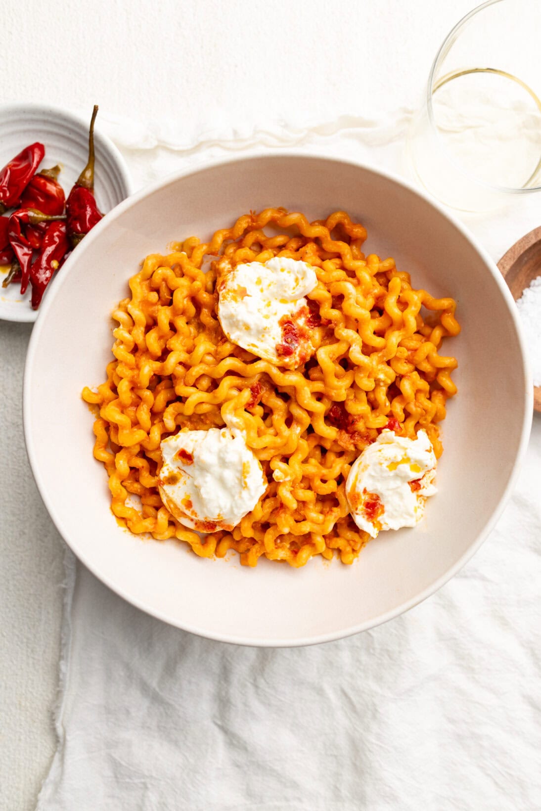 bowl of roasted tomato pasta sauce over long fusilli topped with creamy burrata