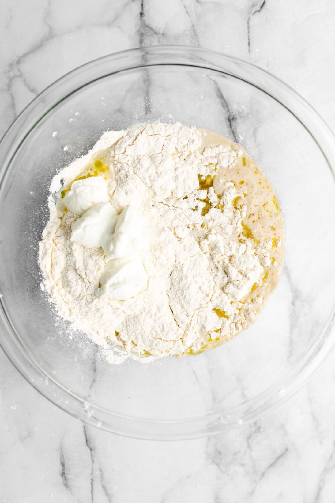 flour, yogurt, and salt added into the bowl of water, yeast, sugar, and olive oil.