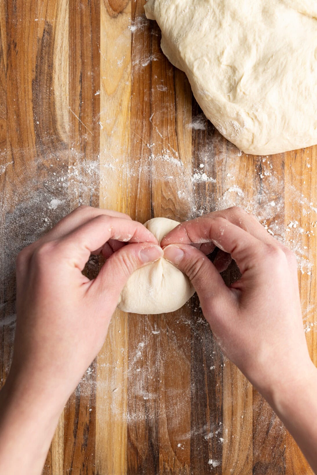 pinching the seam of the dough ball.
