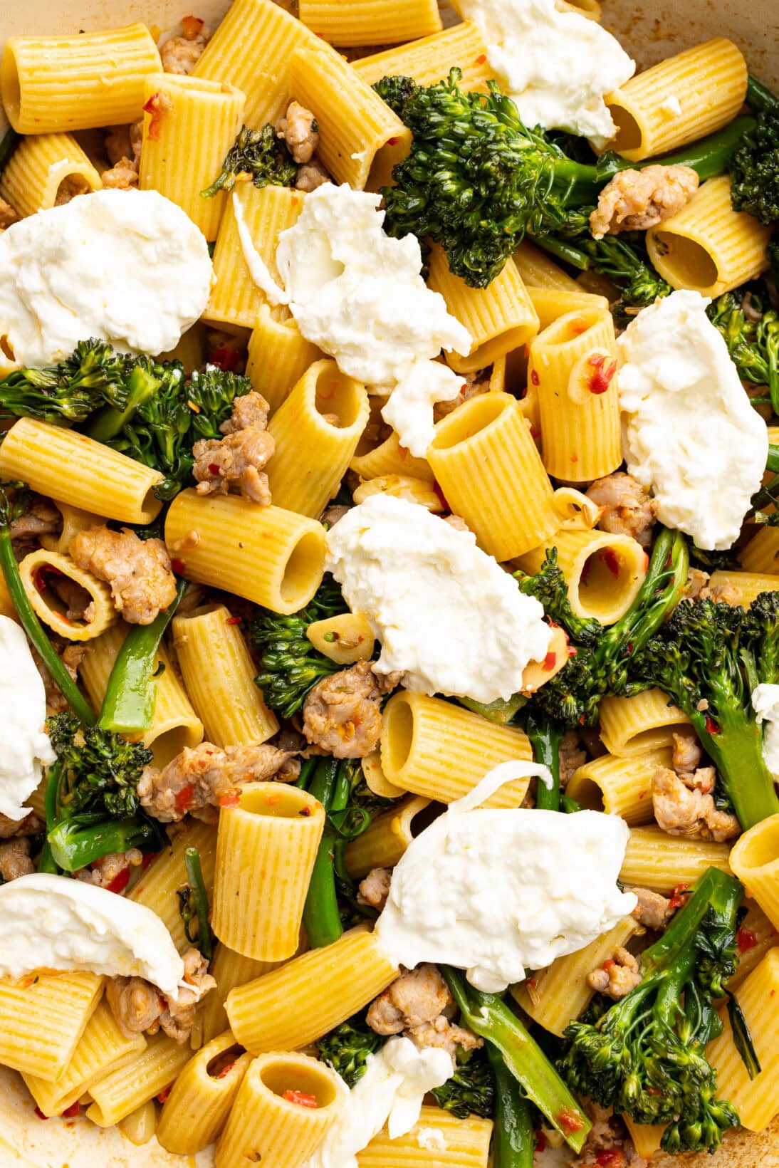 up close of Italian sausage and broccolini pasta in a pan. 