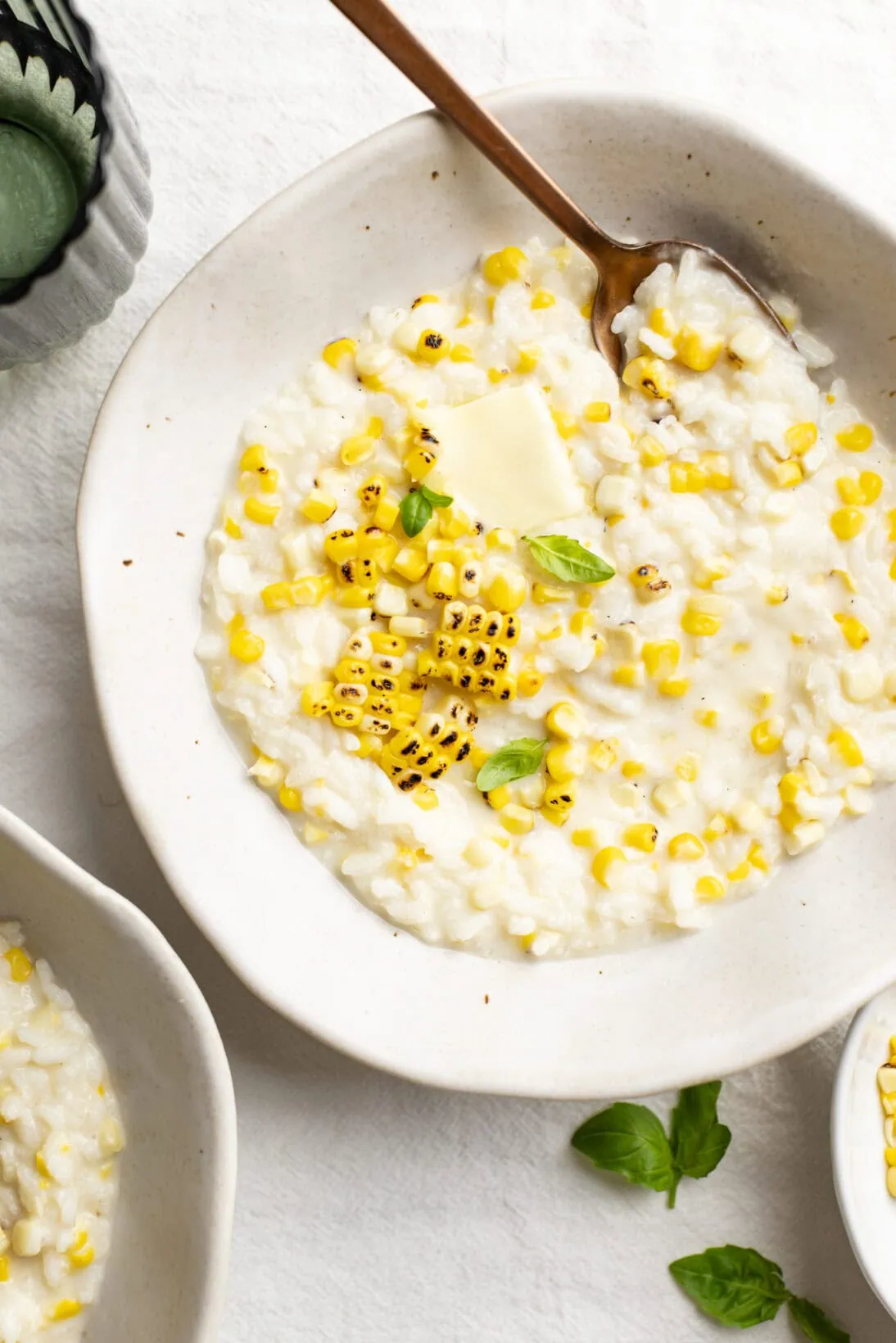 a bowl of sweet corn risotto topped with extra charred grilled corn and a knob of butter.