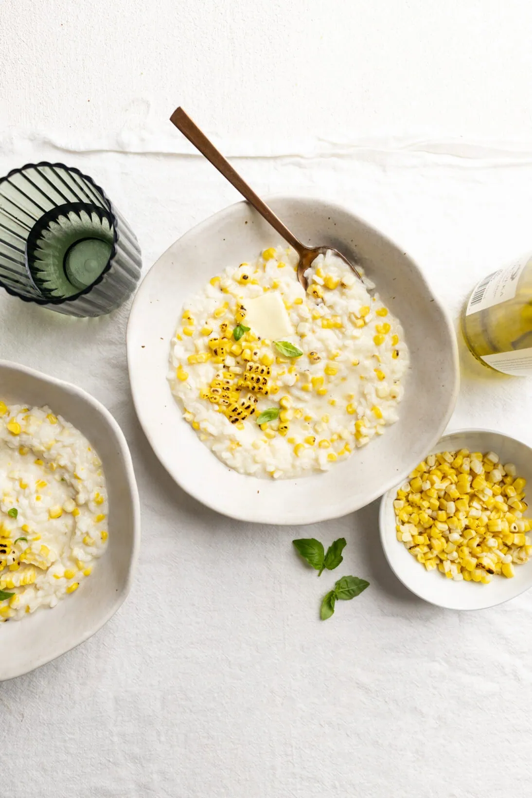 2 bowls of sweet corn risotto topped with extra charred grilled corn and a knob of butter.