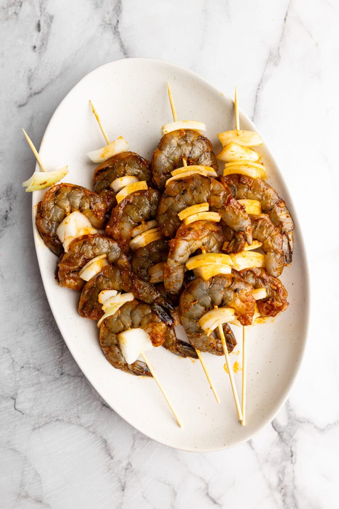 marinating, skewered peri-peri shrimp with onion