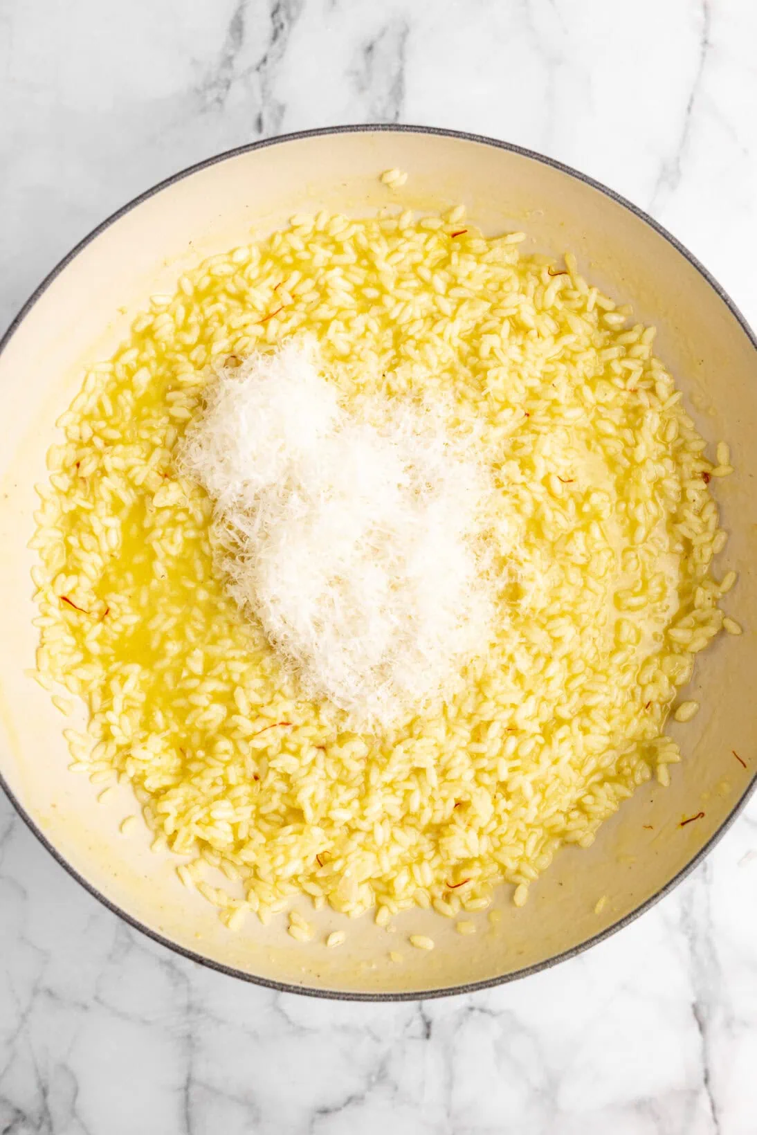cooking risotto alla milanese -adding the cheese to the saffron risotto