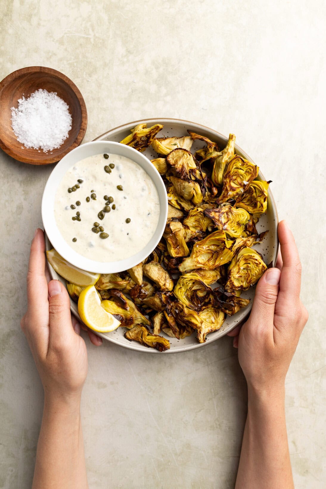 holding a bowl of crispy artichokes with a lemon caper aioli