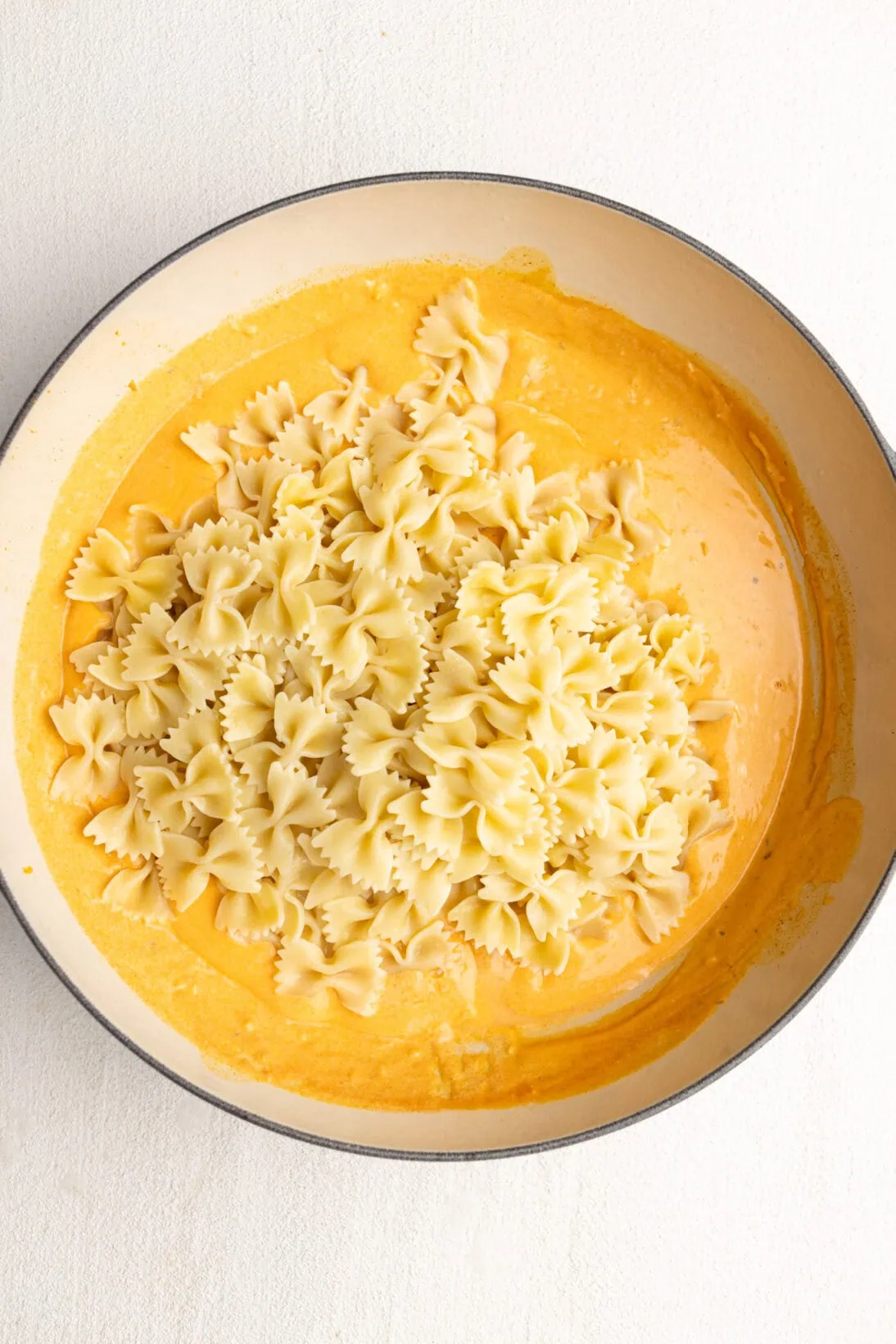 adding pasta to the buffalo chicken pasta sauce.