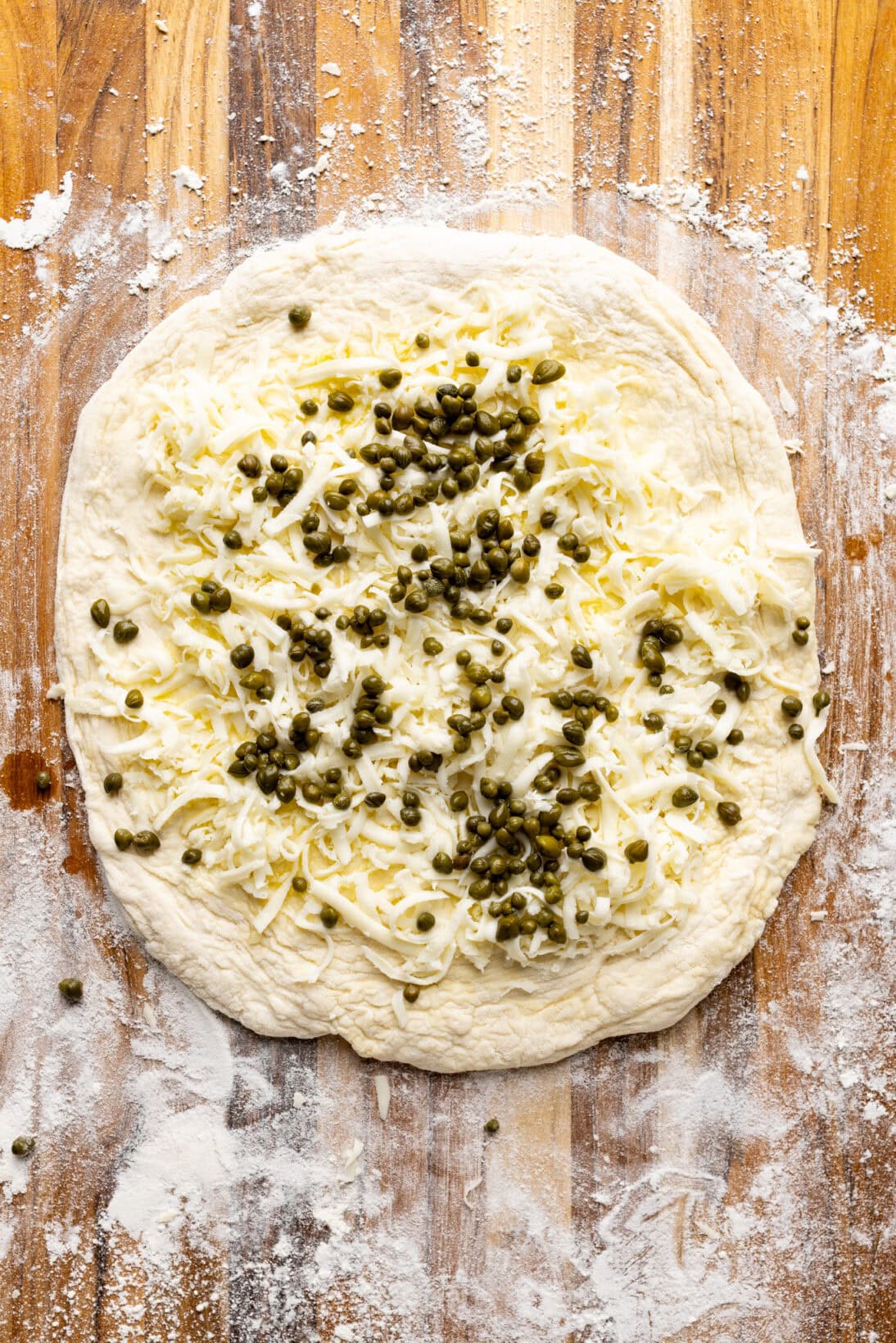 capers, and cheese added to the garlic oil pizza dough 
