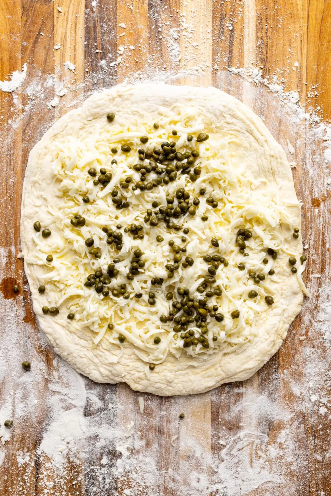 capers, and cheese added to the garlic oil pizza dough 