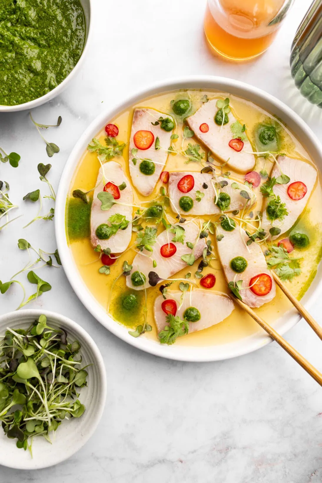Hamachi crudo plated with chilies, jalapeno and cilantro puree and micro greens
