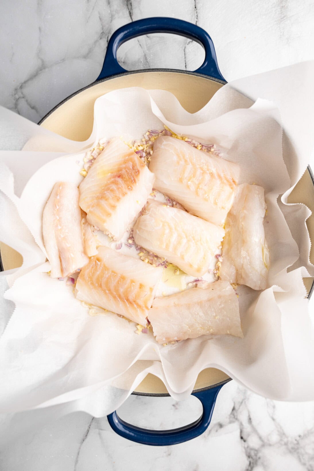 assembling the one pot: the garlic, shallots and fish in the pot over parchment paper.