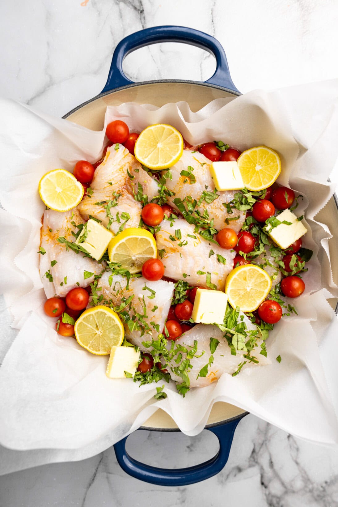 assembling the one pot: the full tomato poached cod assembled with garlic, shallots, cod, tomatoes, basil, lemon and butter.